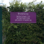 2022 Winchester University Sports Stadium purple and white welcome sign on fence