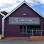2022 Winchester University Sports Stadium grey and white sign tray on purple reception building