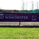 Winchester University Sports Stadium purple and white ACM banner on fence