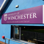 Winchester University Sports Stadium purple and white sign tray on blue reception building